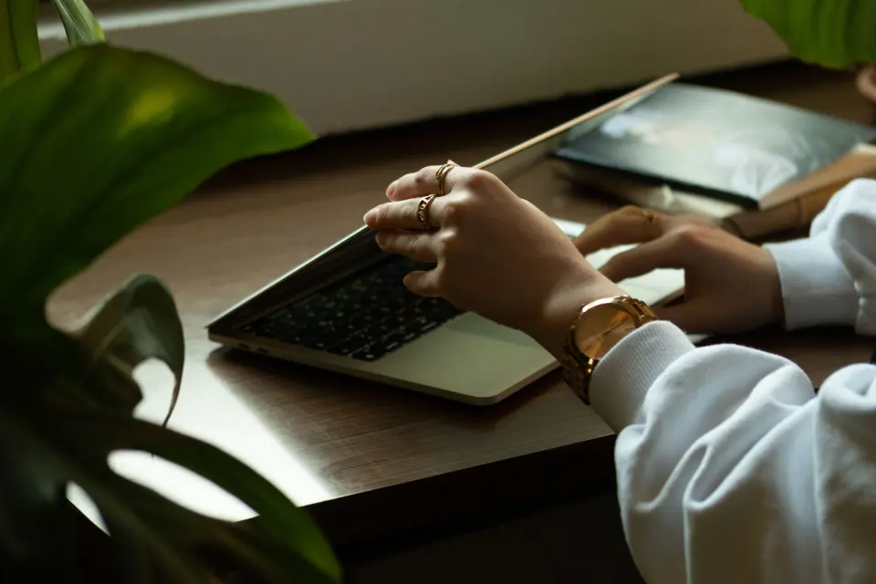Mulher trabalhando online perto de uma janela e plantas